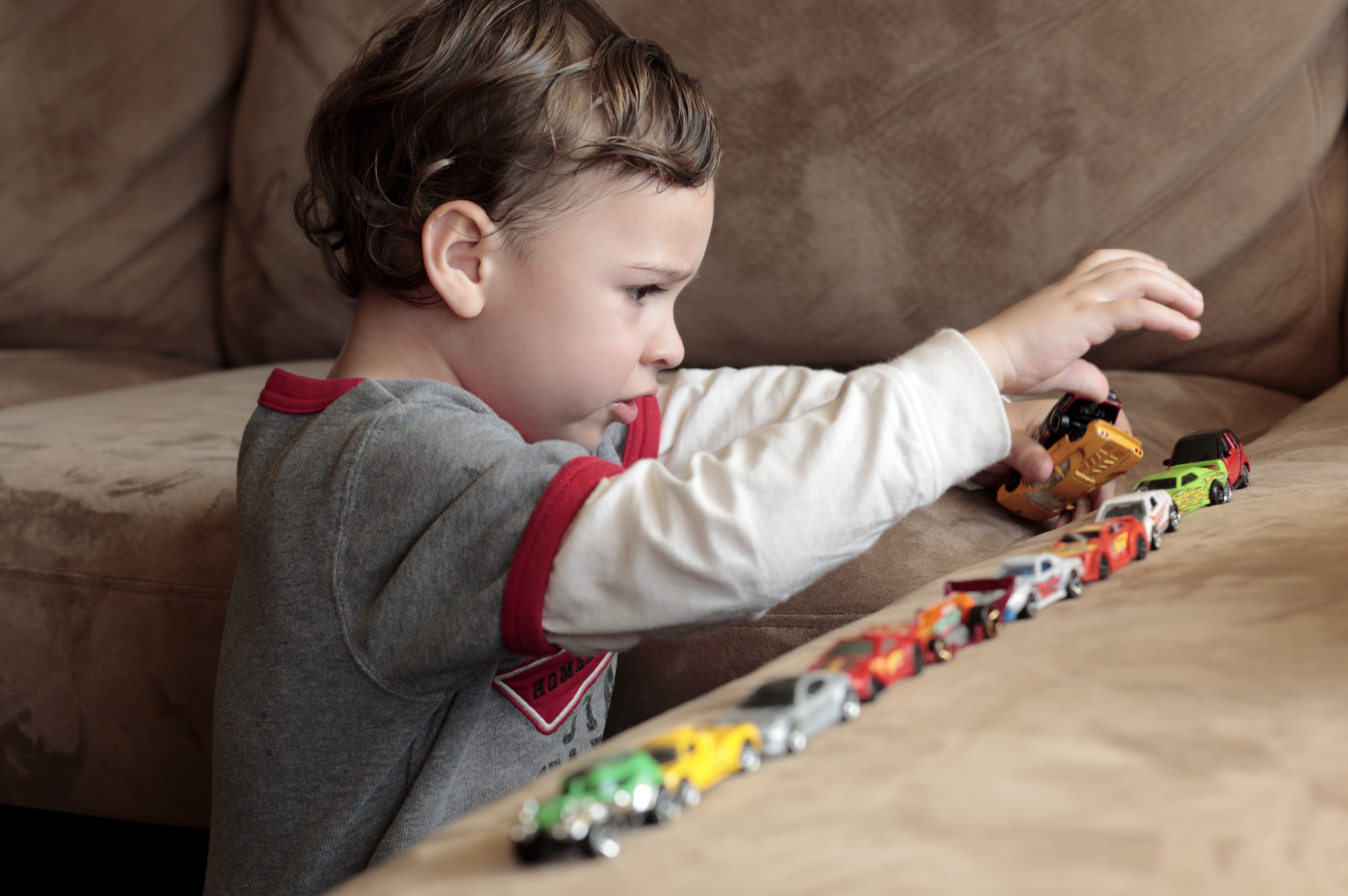 Autistic boy playing with toy cars